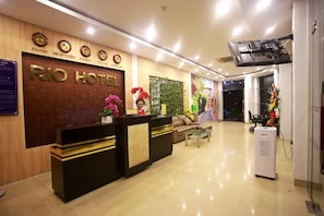 Zona de recepción de hotel con un mostrador de madera, un sofá y una mesa de centro.