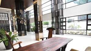 Un interior moderno con una mesa y sillas de madera, ventanas amplias y una estructura decorativa negra.