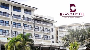Un hotel moderno con varios balcones, piscina y exuberante vegetación tropical.
