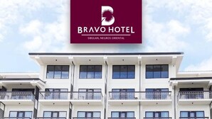 Un edificio de hotel de varios pisos con balcones y un cartel que indica que es el Bravo Hotel en Sibulan, Negros Oriental.