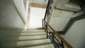 A staircase with a wooden handrail, concrete walls, and a brick pattern on the upper landing. - Give Me 5 Hostel (Chiang Mai)