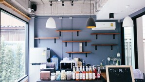 A kitchen area with a refrigerator, microwave, and various bottles on the counter. Shelves are mounted on the wall, and there is a chalkboard with writing. - Give Me 5 Hostel (Chiang Mai)