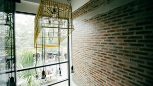 A room with a brick wall, a window with a view of the street, and hanging light fixtures. - Give Me 5 Hostel (Chiang Mai)