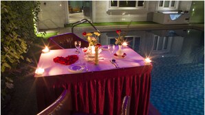 Una mesa para dos con velas, flores y un vaso de agua.