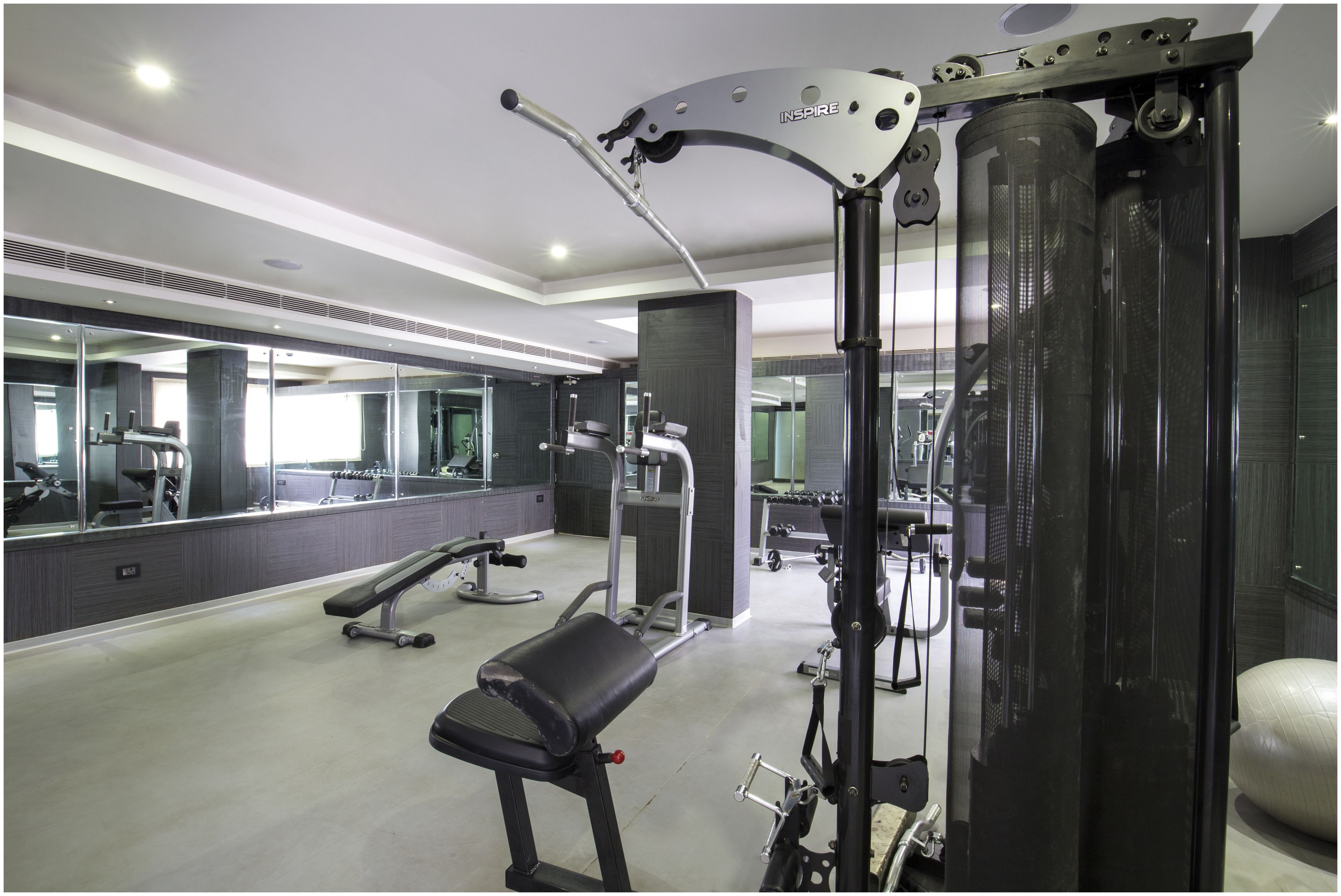 A modern gym with exercise equipment, a bench, and a large mirror.