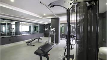 A modern gym with exercise equipment, a bench, and a large mirror.