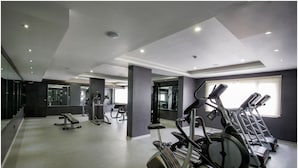 Un gimnasio con equipo de ejercicio, un espejo grande y una ventana con luz natural.