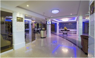 A hotel lobby with a reception desk, seating area, and a chandelier.