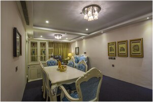 A dining room with a white table, blue upholstered chairs, and a chandelier.