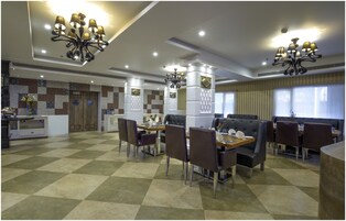 Un comedor espacioso con techos altos, candelabros y piso de tablones de ajedrez.