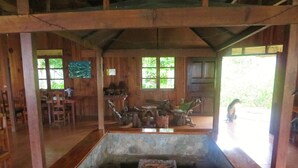 A rustic wooden interior with a stone basin in the center, wooden furniture, and large windows allowing natural light. - Native Village Inn (Banaue)