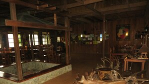 A rustic interior with wooden beams, a stone fish tank, and antler sculptures. - Native Village Inn (Banaue)