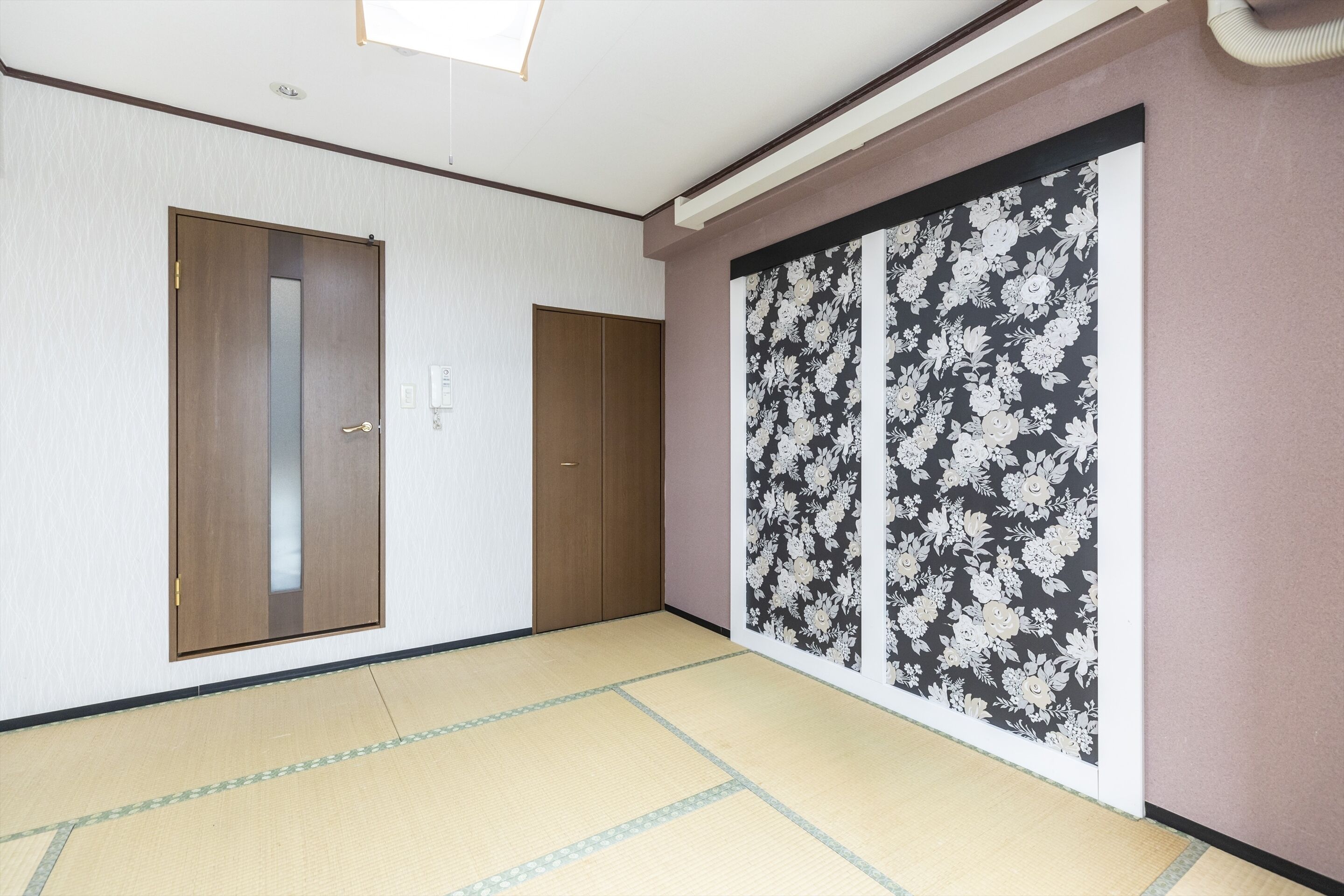 A room with tatami flooring, a wooden door, and a sliding shoji screen with floral patterns.