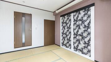 A room with tatami flooring, a wooden door, and a sliding shoji screen with floral patterns.