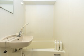 A bathroom with a sink, faucet, and a bathtub. There are four bottles of shampoo or conditioner on the edge of the bathtub. - Hotel SSK Osaka Naniwa (Osaka)