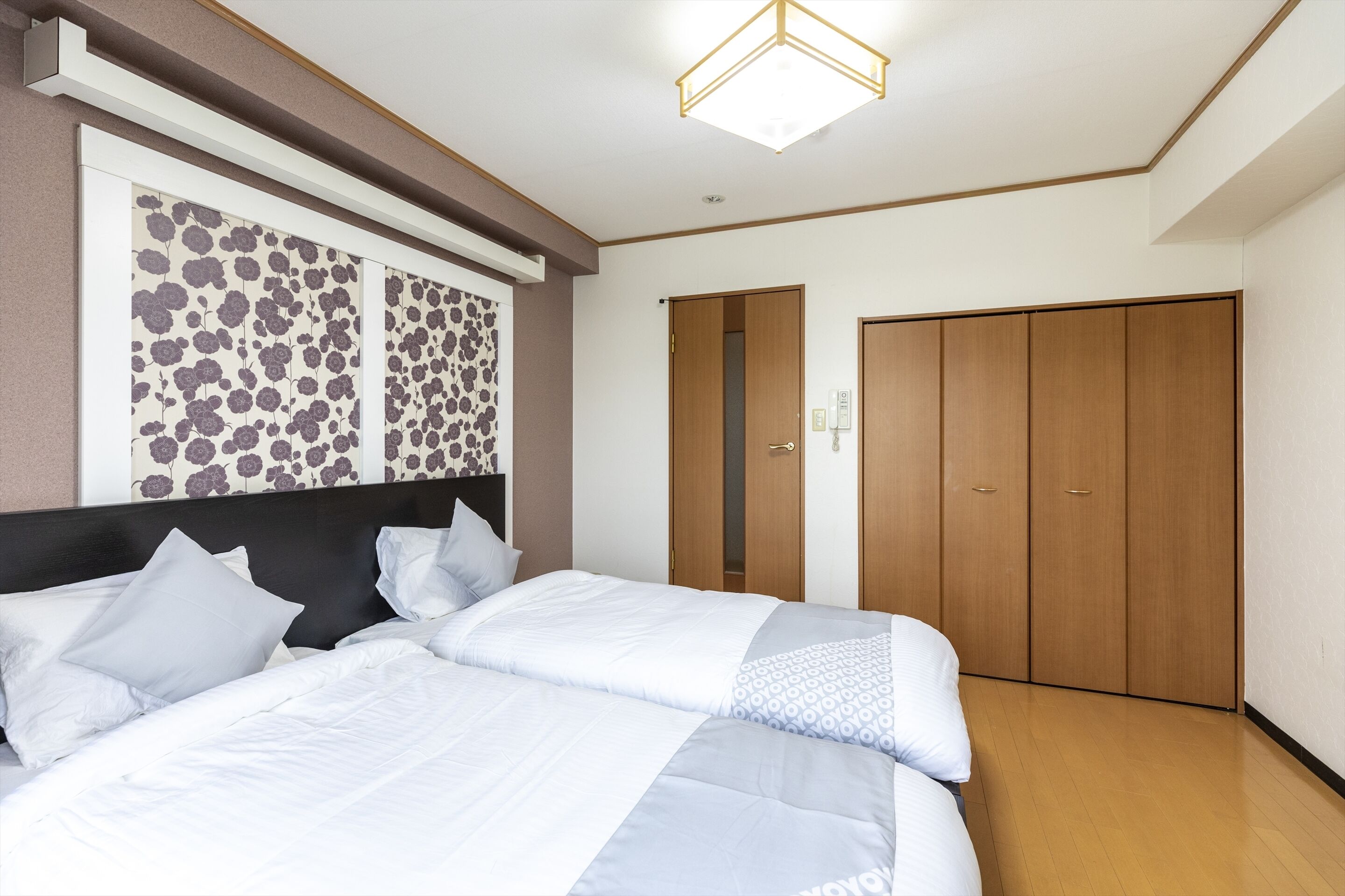 A hotel room with a large bed, a wardrobe, and a wall-mounted artwork.