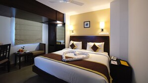 Una habitación de hotel con cama, mesita de noche, lámpara y ventilador de techo.