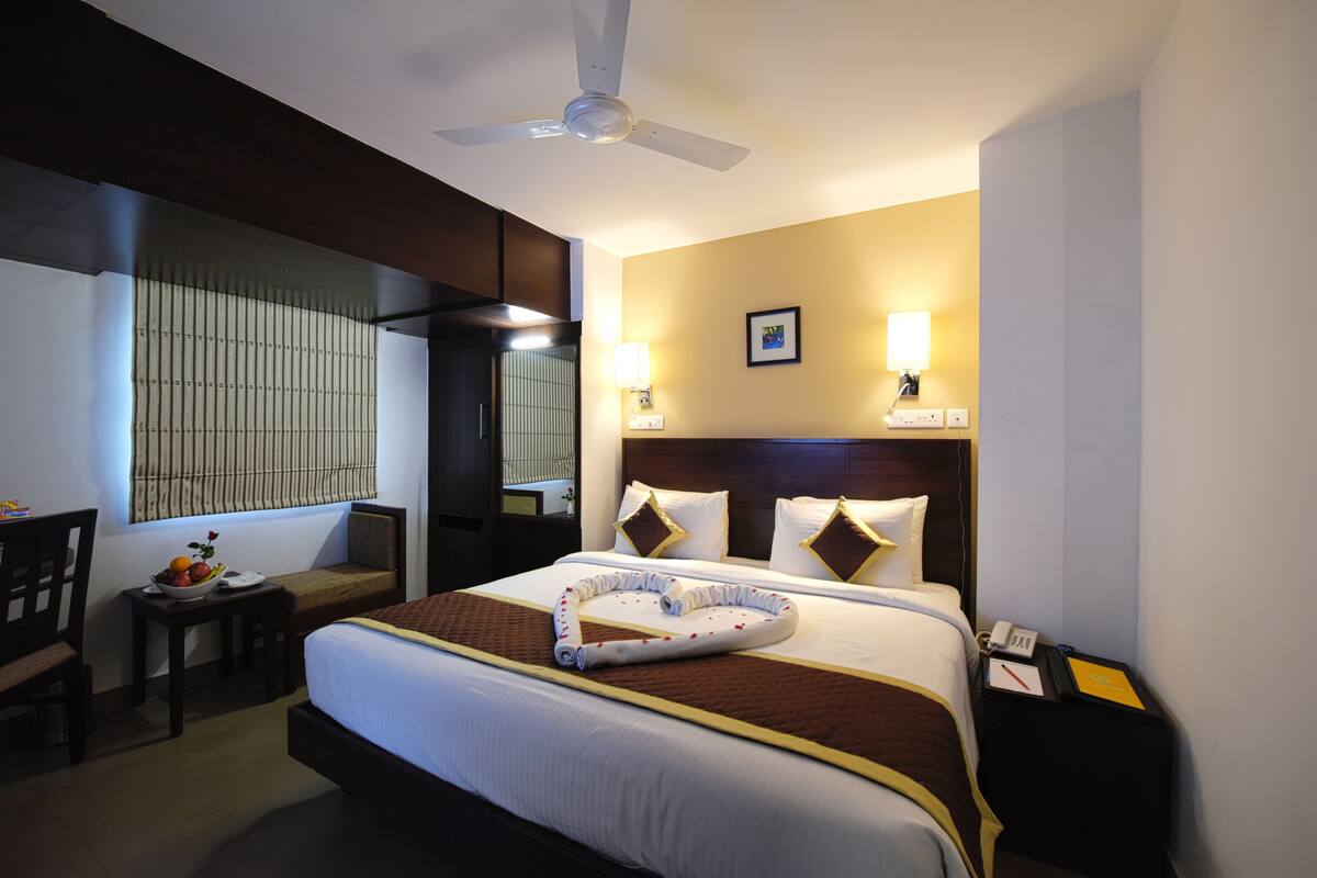 Une chambre d’hôtel équipée d’un lit, d’une table de chevet, d’une lampe et d’un ventilateur de plafond.