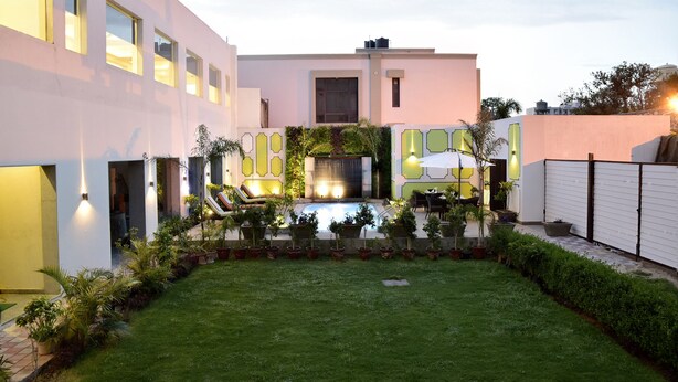 Un edificio moderno con piscina, plantas en macetas y mobiliario de exterior.