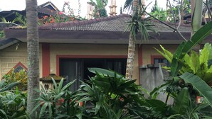 A house with a tiled roof, surrounded by lush tropical plants. - Pacung Indah Hotel and Restaurant (Baturiti)