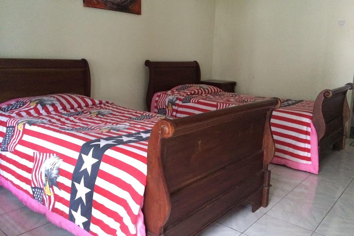 Ein Zimmer mit drei hölzernen Betten, jeweils mit einer rot-weiß gestreiften Tagesdecke und einem Design mit amerikanischer Flagge.