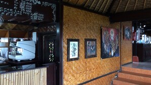A coffee shop interior with a bamboo wall, a coffee machine, and framed artwork. - Pacung Indah Hotel and Restaurant (Baturiti)