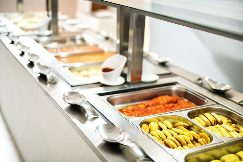 Un buffet proposant une variété de plats, notamment des bananes, un plat rouge et un récipient contenant une sauce blanche.