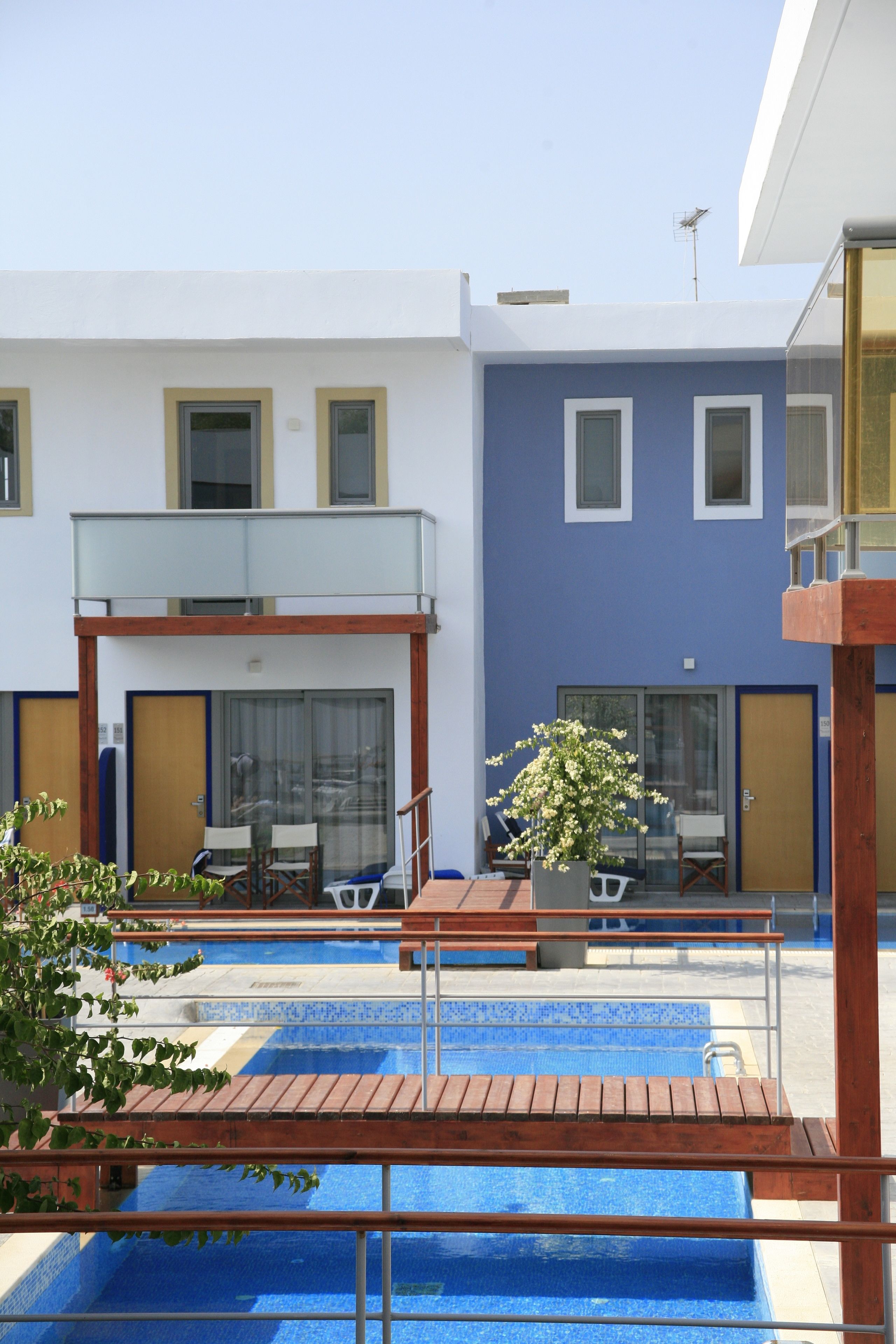 A modern hotel with a pool area, outdoor seating, and a two-story structure.