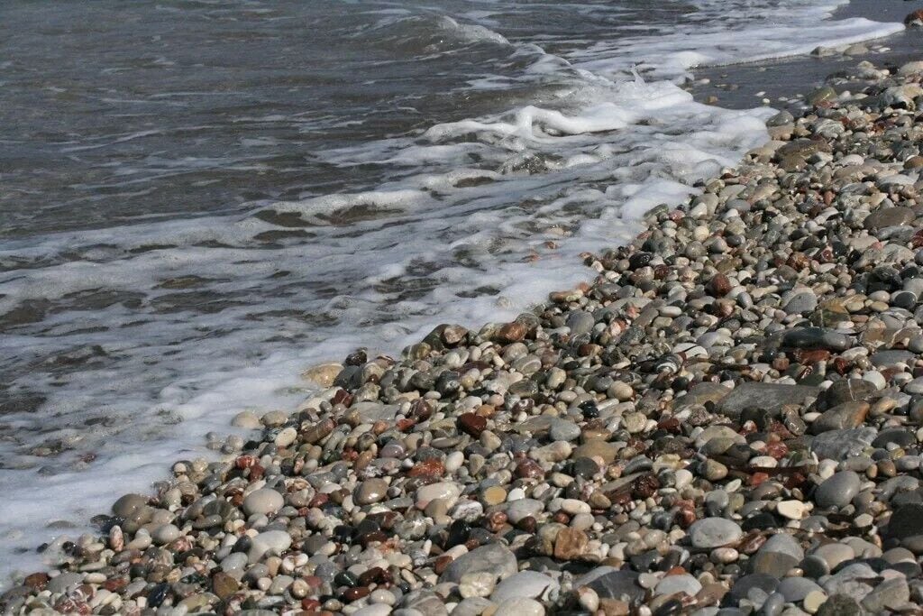 A pebbled beach with waves gently lapping at the shore.