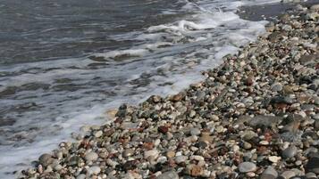 A pebbled beach with waves gently lapping at the shore.