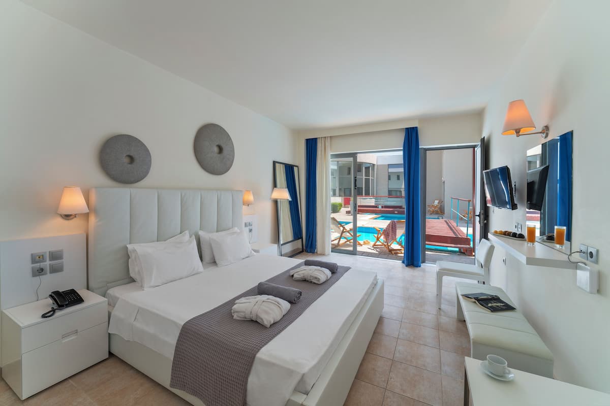 Une chambre d’hôtel moderne dotée d’un grand lit, d’un bureau, d’une chaise et offrant une vue sur une piscine extérieure.