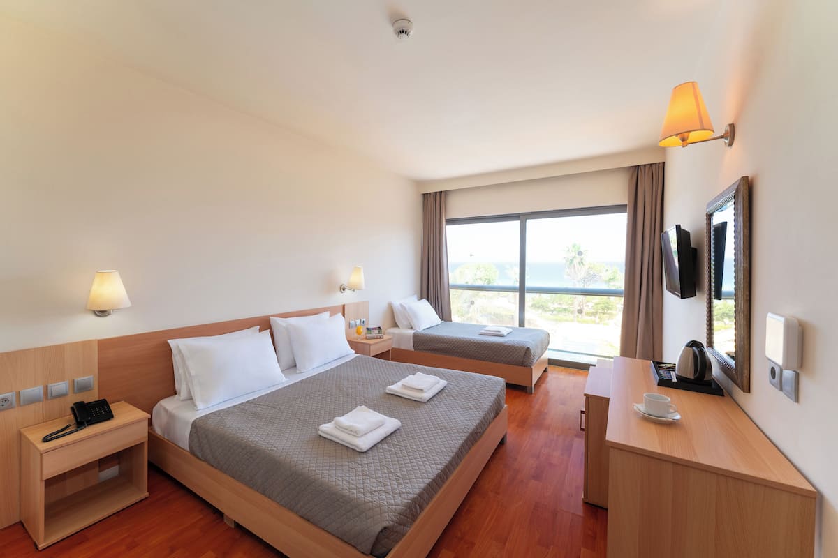 Une chambre d’hôtel avec deux lits, un bureau, une télévision et une fenêtre donnant sur un paysage agréable.