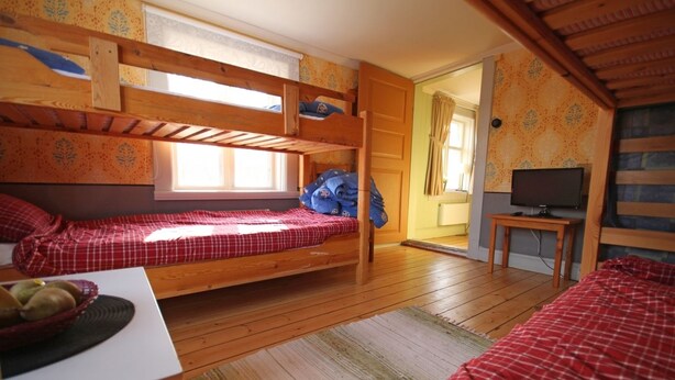 A room with two bunk beds, a television, and a small table with a basket of fruit. - Mallboden Café & Vandrarhem (Motala)