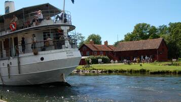 A riverboat named 'DIANA' docked at a pier with a red barn and a grassy area in the background.