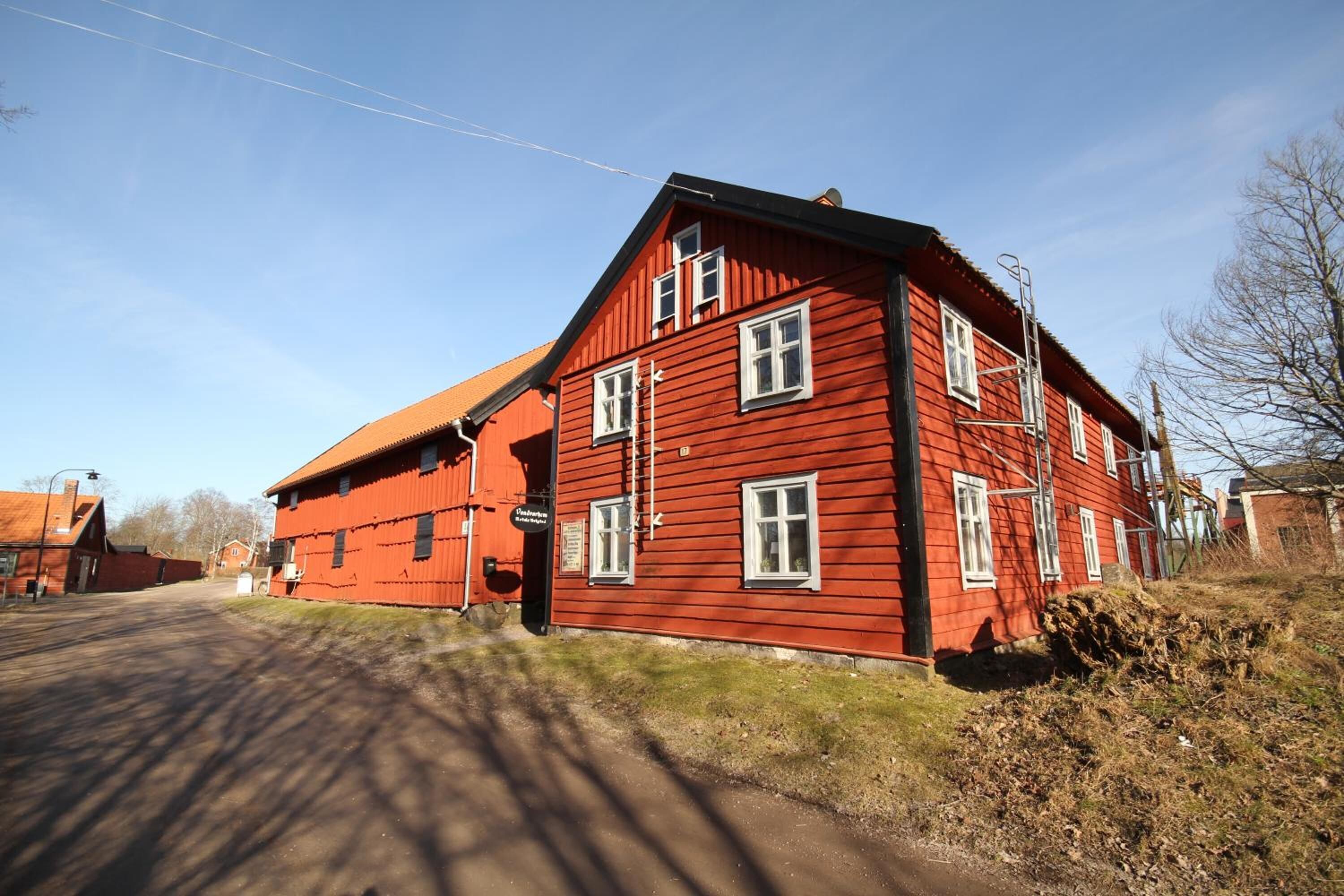 A red wooden building with multiple windows and a sloped roof.