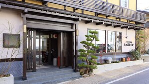 A traditional Japanese building with a wooden entrance, a small garden with a bonsai tree, and a sign in Japanese. - Kusatsu Onsen 326 Yamanoyu Hotel (Kusatsu)