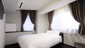 A hotel room with a bed, a bedside table, a TV, and curtains. - Kusatsu Onsen 326 Yamanoyu Hotel (Kusatsu)