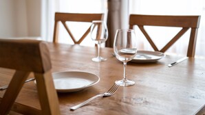 A wooden dining table with two chairs, a wine glass, a fork, and a plate. - Bliss Cottage SAKURA (Kutchan)