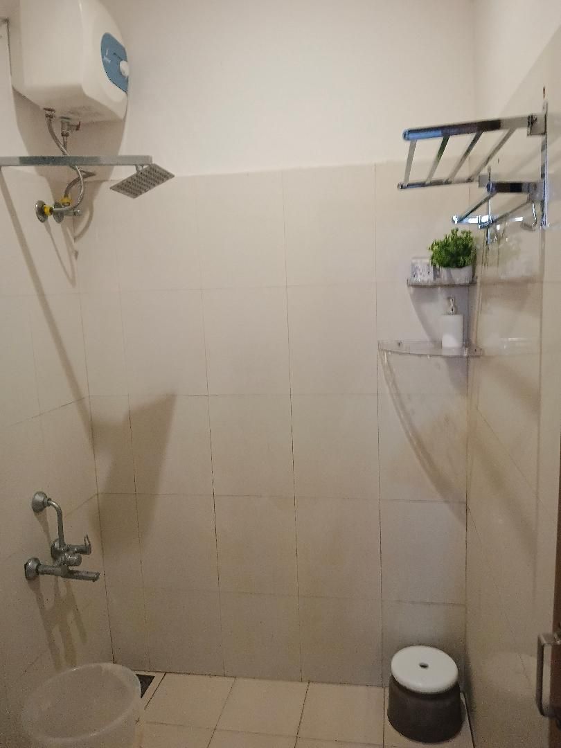 A small, tiled bathroom with a shower, a toilet, and a sink.