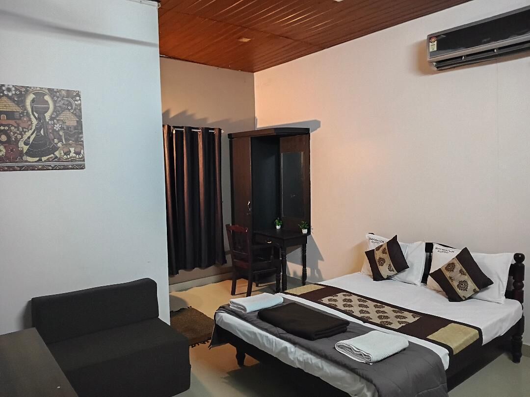 A bedroom with a bed, a desk, a chair, and a painting on the wall.