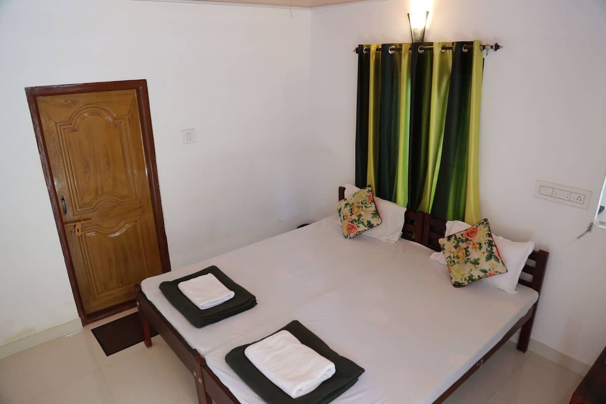 A neatly made bed with pillows, a wooden door, and a curtain.
