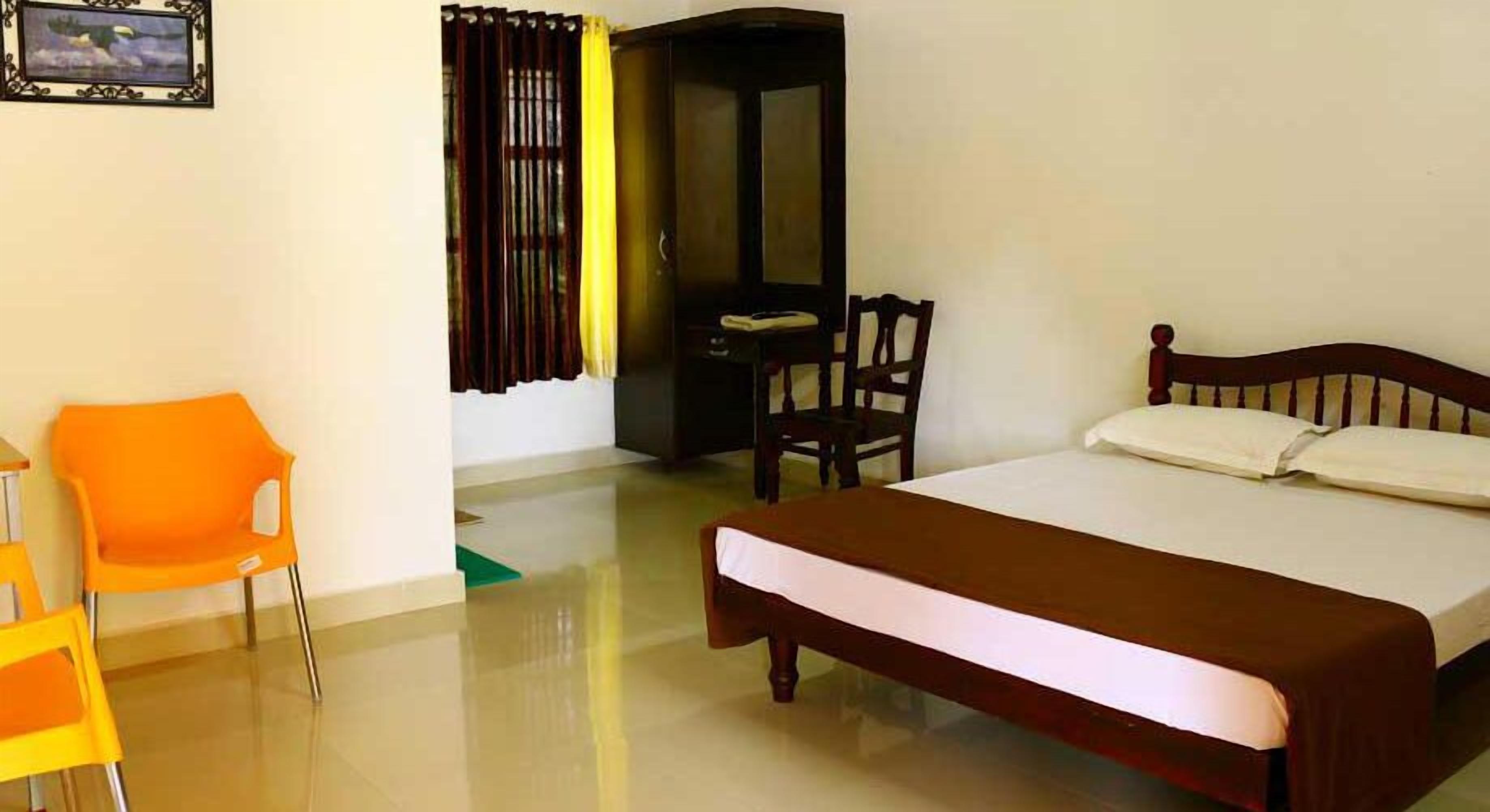 A bedroom with a bed, a desk, and two chairs.