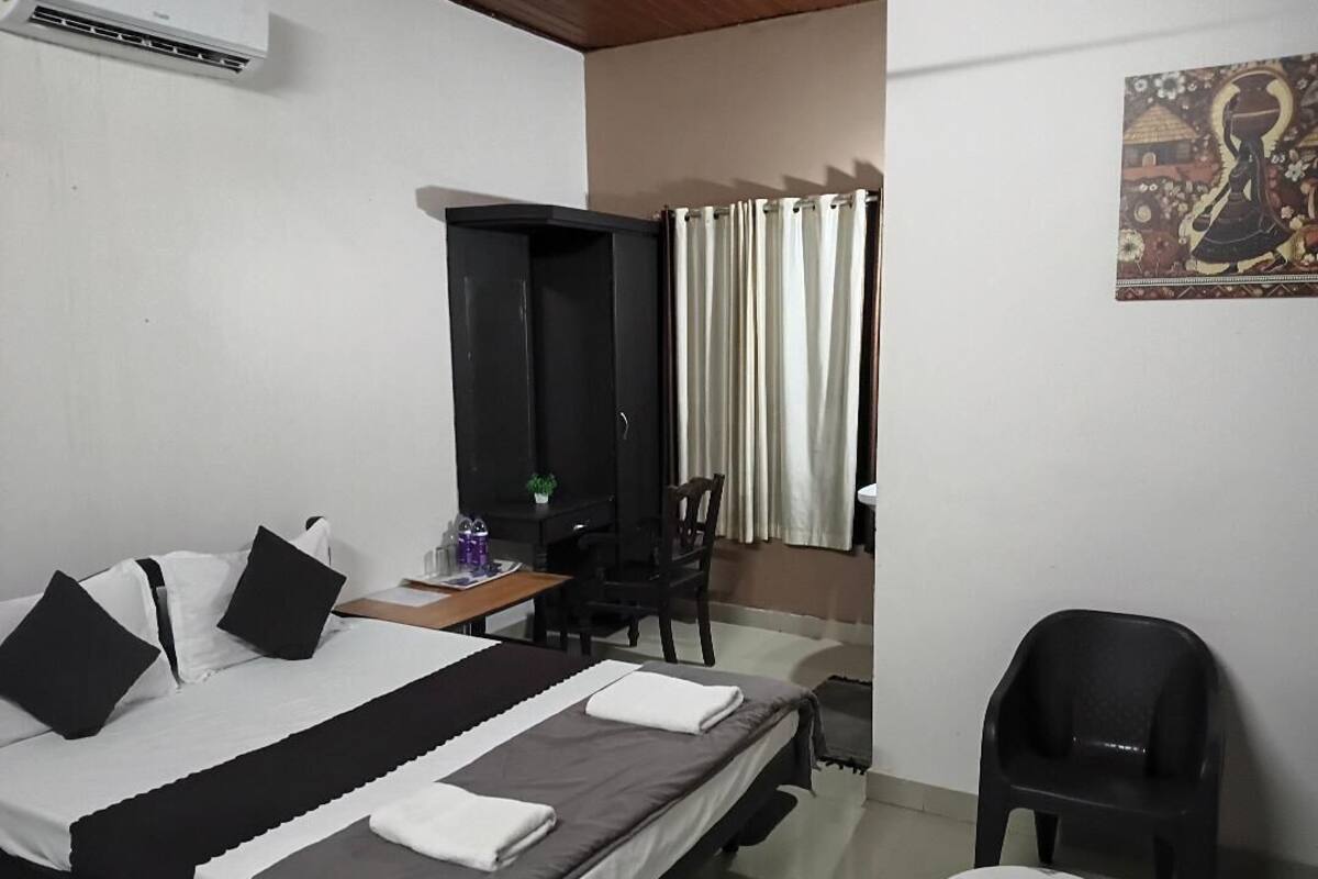 A hotel room with a bed, a desk, a chair, and a small table.