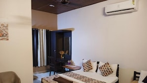 A bedroom with a bed, bedside table, chair, and a desk with a chair. - Baywatch Beach Resort (Ambalapuzha)