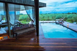 Una piscina al aire libre, sillones reclinables de piscina