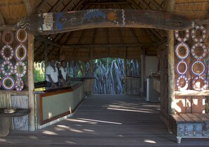 An indoor wooden structure with a thatched roof, a reception desk, and decorative circular patterns on the walls. - Selinda Camp (Selinda Reserve)