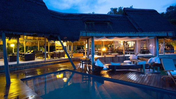 An infinity pool with wooden deck seating and a bar area. - Selinda Camp (Selinda Reserve)