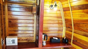 Una cocina compacta con paredes de madera, un refrigerador negro, un cubo de basura y una pequeña mesa de madera.