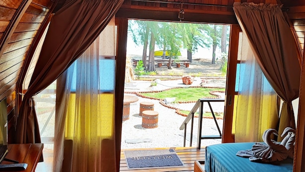 Acogedora habitación tipo cabaña de madera con cama, un banco y vistas al exterior.