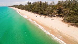 Una playa con aguas turquesas cristalinas, una orilla arenosa y una hilera de árboles.